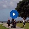Family walking in a park with video icon.